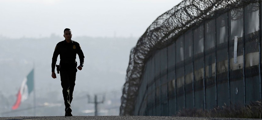 A CBP agent walks along the border fence in 2015 near San Diego.