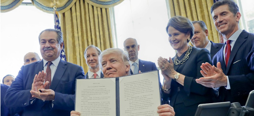 Trump holds up his executive order creating regulatory reform task forces. 