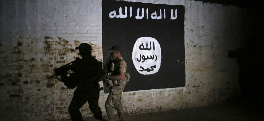 An Iraqi soldier inspects a recently-discovered train tunnel, adorned with an Islamic State group flag in March.