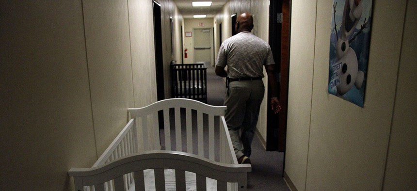 A federal employee walks past cribs inside of the barracks for law enforcement trainees turned into immigrant detention center at the Federal Law Enforcement Center (FLETC) in Artesia, N.M. in 2014.