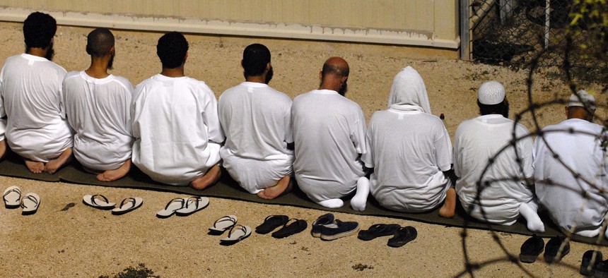 A group of detainees kneel as they observe morning prayer before sunrise inside Camp Delta in 2009.