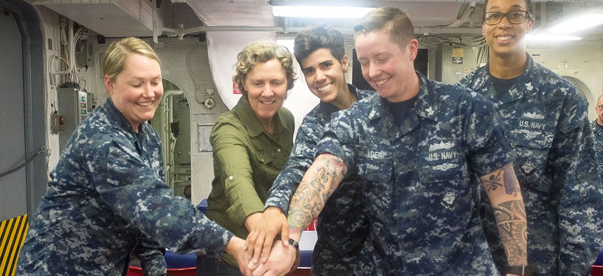 Command Master Chief (Ret.) Kathleen Henson, from Midland, Mich.,, center, and USS Makin Island Sailors cut a cake during the Lesbian, Gay, Bisexual, and Transgender Pride Month observance in June.