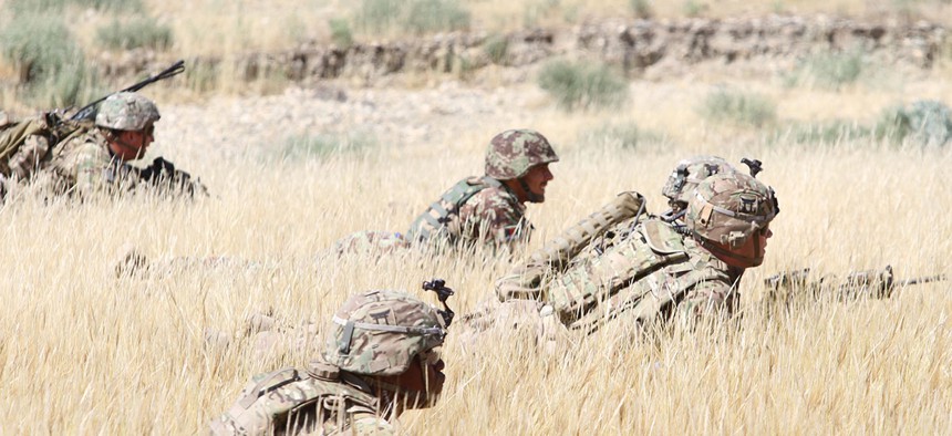 Soldiers wait in the tall grass with their Afghan National Army counterpart during a combined arms live fire training exercise in Laghman province in 2015.