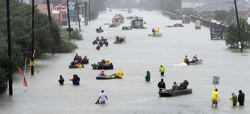 Rescue boats fill a flooded street at flood victims are evacuated as floodwaters from Tropical Storm Harvey rise Monday.