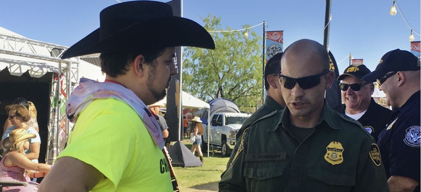 A U.S. Border Patrol agent gives information about working for the agency to Ric Kindle in April, at the Country Thunder Music Festival in Florence, Ariz. 