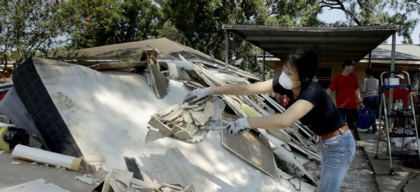 Lucy Liu dumps trash on a pile of debris as she helps her co-worker Tianna Oliver clean out her flood-damaged house Aug. 31 in Houston. 