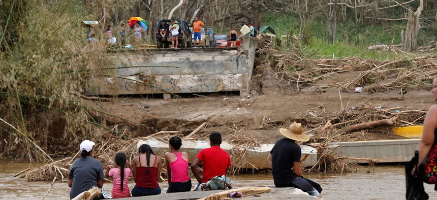 People sit on both sides of a destroyed bridge that crossed over the San Lorenzo de Morovis river, in the aftermath of Hurricane Maria, in Morovis, Puerto Rico.