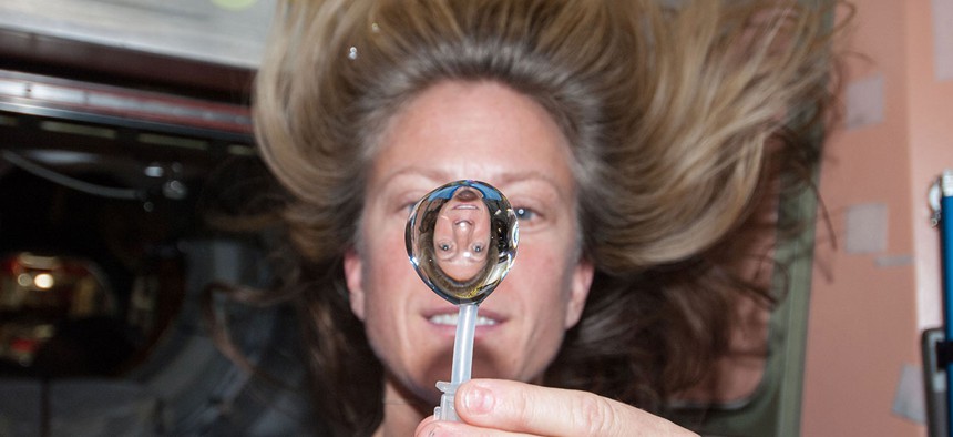 NASA astronaut Karen Nyberg, Expedition 36 flight engineer, squeezes a water bubble out of her beverage container, showing her image refracted, in the Unity node of the International Space Station in 2013.