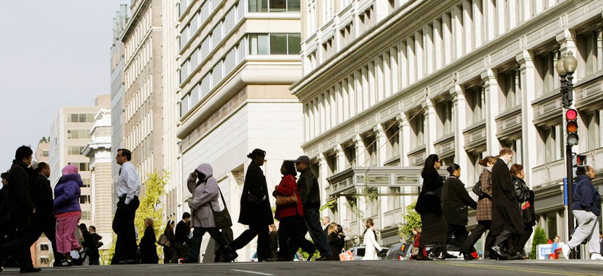 Pedestrians walk across the street at the intersection of 13th and E streets NW, in downtown Washington.