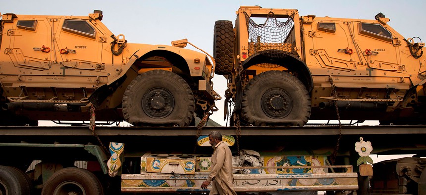 In this Nov. 26, 2013, file photo, a Pakistani man walks by a truck carrying NATO military vehicles at a terminal in Karachi, Pakistan.