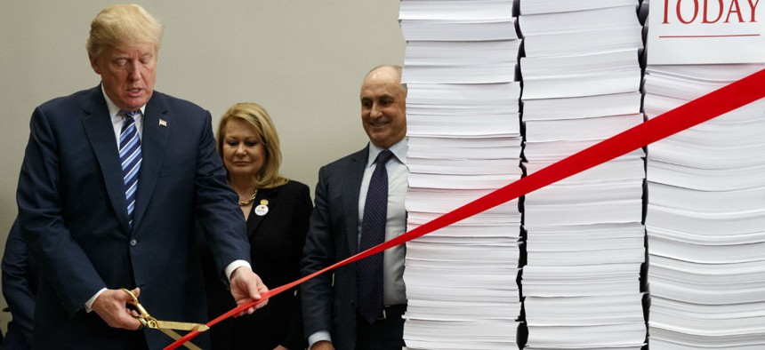 President Trump symbolically cuts red tape during a December event to tout the administration's regulatory reforms. 