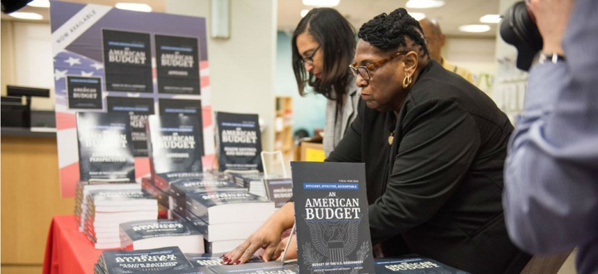 Federal workers put out copies of the Trump administration's FY2019 budget proposal.