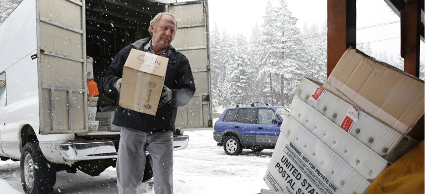 Postal worker Rex Harrison unloads his vehicle at the post office at Soda Springs, Calif., in 2016.