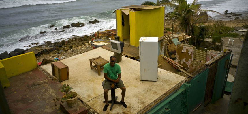 Roberto Figueroa Caballero sits on a table in his home that was destroyed by Hurricane Maria in the La Perla neighborhood on the coast of San Juan, Puerto Rico. 