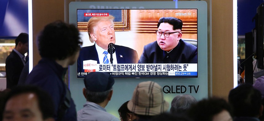 People watch a TV screen showing file footage of U.S. President Donald Trump, left, and North Korean leader Kim Jong-un in Seoul on Wednesday.