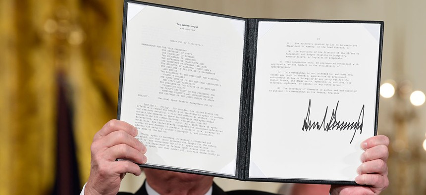President Donald Trump shows off a "Space Policy Directive" after signing it during a meeting of the National Space Council 