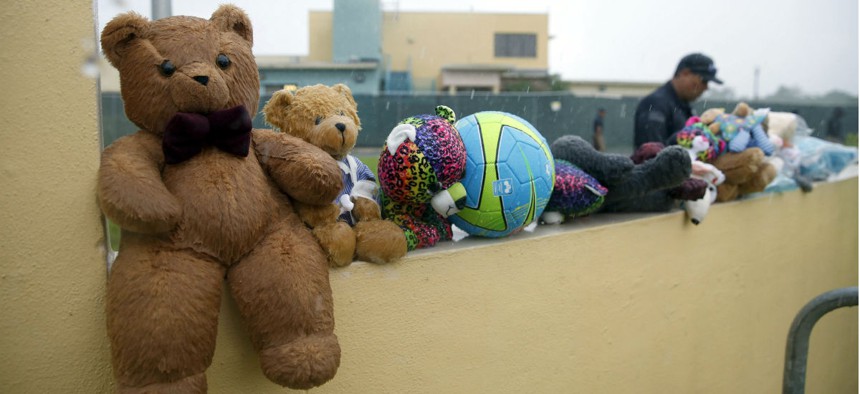 A guard walks past toys donated by protesters outside the Homestead Temporary Shelter for Unaccompanied Children in Florida.