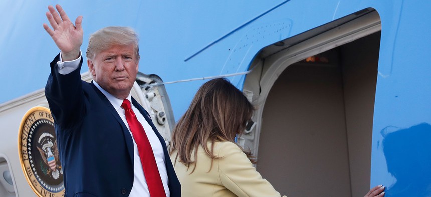 Donald Trump waves when boarding Air Force One as he leaves with his wife Melania, right, from the airport in Helsinki on Monday.