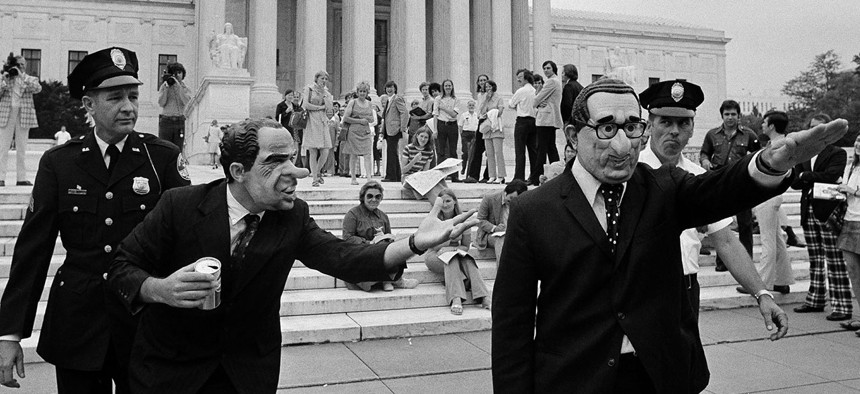 Two demonstrators, one, left, wearing a President Nixon mask and the other wearing a Secretary of State Henry Kissinger mask and giving a Nazi salute, are escorted by police from in front of the Supreme Court building in Washington, July 24, 1974.