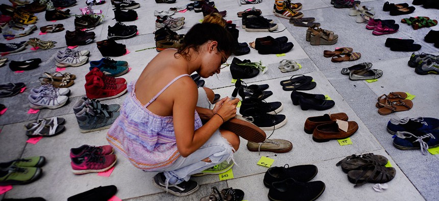 A woman places one of the hundreds of shoes in memory of those killed by Hurricane Maria in front of the Puerto Rico Capitol, in San Juan on June 1, 2018.