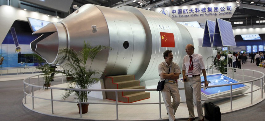 In this Nov. 16, 2010 file photo, visitors sit beside a model of China's Tiangong-1 space station at the 8th China International Aviation and Aerospace Exhibition in Zhuhai in southern China's Guangdong Province.