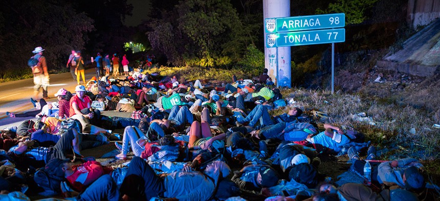 Early in the morning migrants sleep next to the highway, as a thousands-strong caravan of Central American migrants slowly makes its way toward the U.S. border, between Pijijiapan and Arriaga, Mexico on Friday.