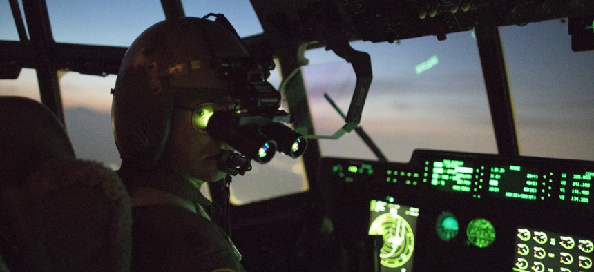 A C-130J pilot wears night vision goggle during a training mission above Yokota Air Base, Japan.