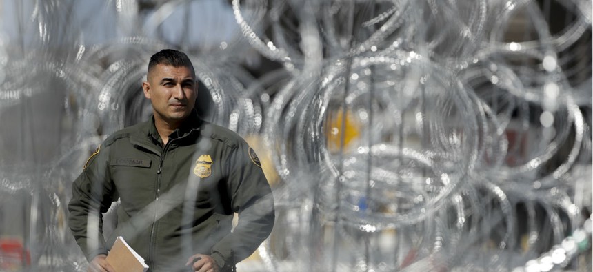 A U.S. Border Patrol agent looks through concertina wire during a tour of the San Ysidro port of entry on Nov. 16, 2018, in San Diego.