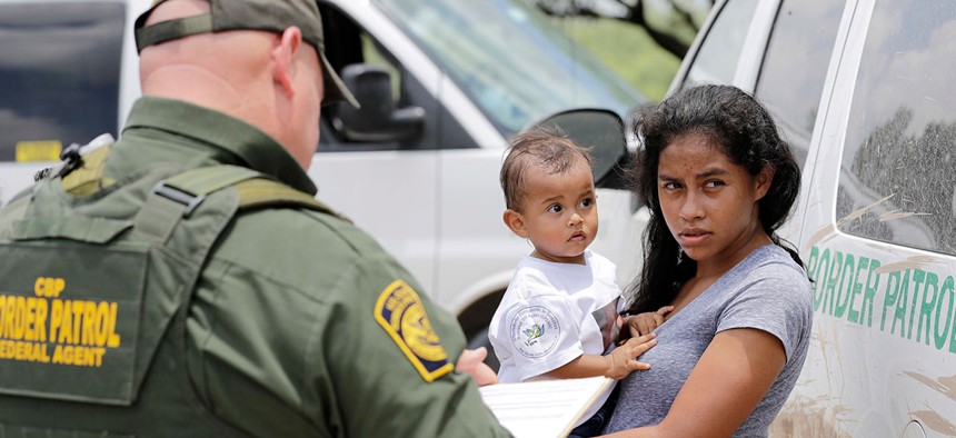 A mother migrating from Honduras holds her 1-year-old child as surrendering to U.S. Border Patrol agents after illegally crossing the border near McAllen, Texas in June.