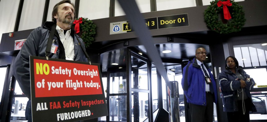 FAA employee Michael Jessie, who is currently working without pay as an aviation safety inspector for New York international field office overseeing foreign air carriers, holds a sign at Newark Liberty International Airport Jan. 8.