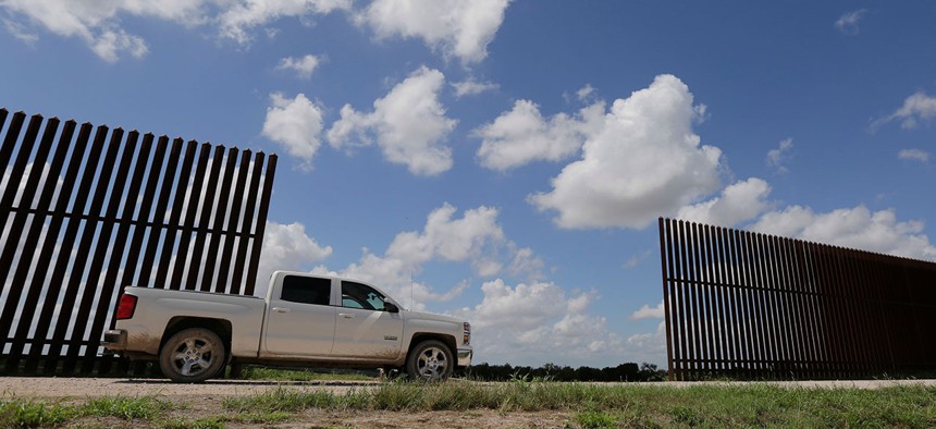 A farmer passes along a border fence that divides his property in Mission, Texas in 2015.