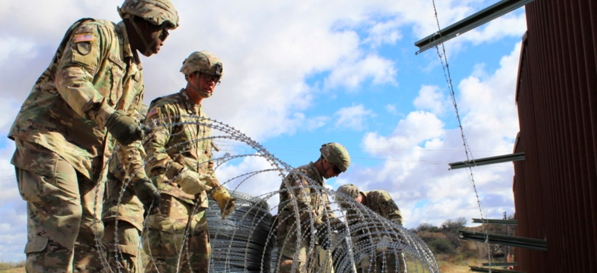 Engineers from 937th Clearance Company prepare to place concertina wire on the Arizona-Mexico border wall, Dec. 1, 2018.