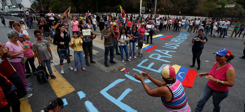 People stand around the message "Get out usurper!" as they protest the government of Venezuela's President Nicolas Maduro in Caracas on Tuesday