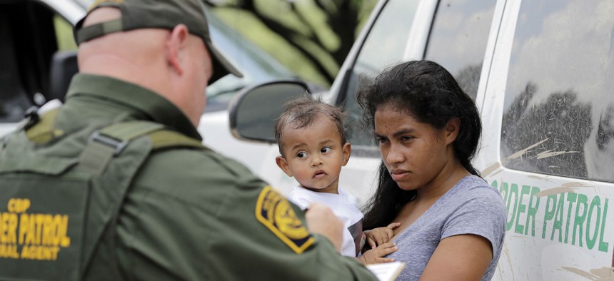 A mother migrating from Honduras holds her 1-year-old child as surrendering to U.S. Border Patrol agents after illegally crossing the border June 25, 2018, near McAllen, Texas.