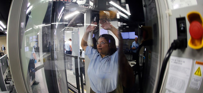 A Transportation Security Administration officer candidate passes through a body scanner as she plays the part of an air traveler in a 2016 training session in Georgia.