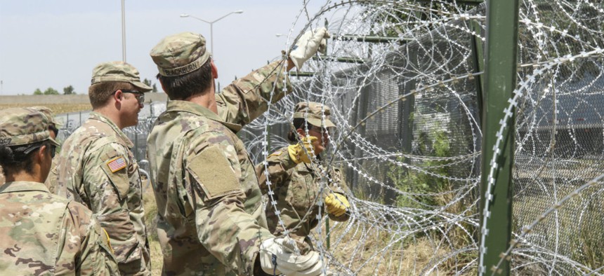 Soldiers from the 161st Engineer Support Company (Airborne) stretch out concertina wire to secure to the existing border fence near the World Trade International Bridge in Laredo, Texas