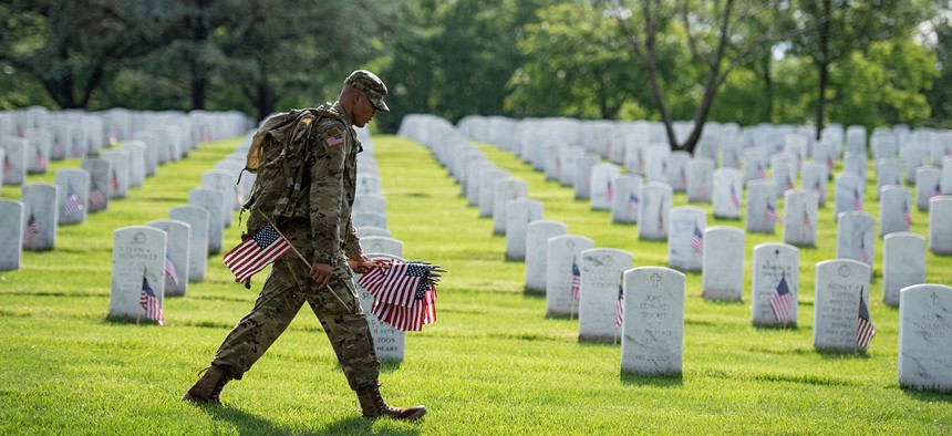 Soldiers from the 3d U.S. Infantry Regiment (The Old Guard) place U.S. flags at headstones as part of Flags-In at Arlington National Cemetery, Arlington, Virginia, May 23, 2019
