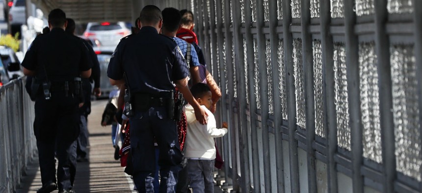 Customs and Border Protection officers escort migrants being taken to apply for asylum in the United States, on the International Bridge 1 in Nuevo Laredo, Mexico. 