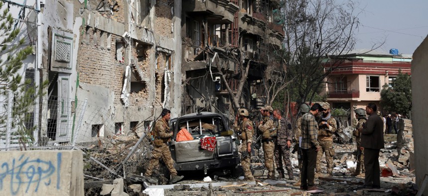 Afghan security forces inspect the aftermath of Sunday's attack in Kabul on Monday.