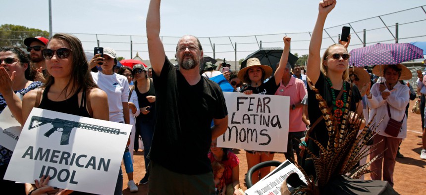 Demonstrators hold signs and raises their fists to protest the visit of President Donald Trump on Wednesday in El Paso.