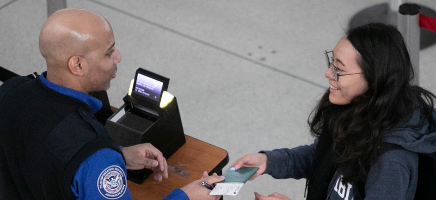A Transportation Security Administration agent reviews a passenger's ID and ticket at a security checkpoint at New York's John F. Kennedy International Airport. 