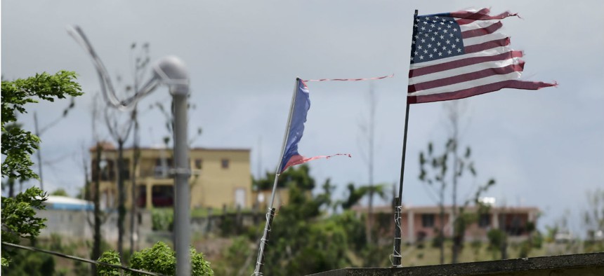 In this May 2018 photo, deteriorated U.S. and Puerto Rico flags fly in an area that remained without power eight months after Hurricane Maria devastated the island.