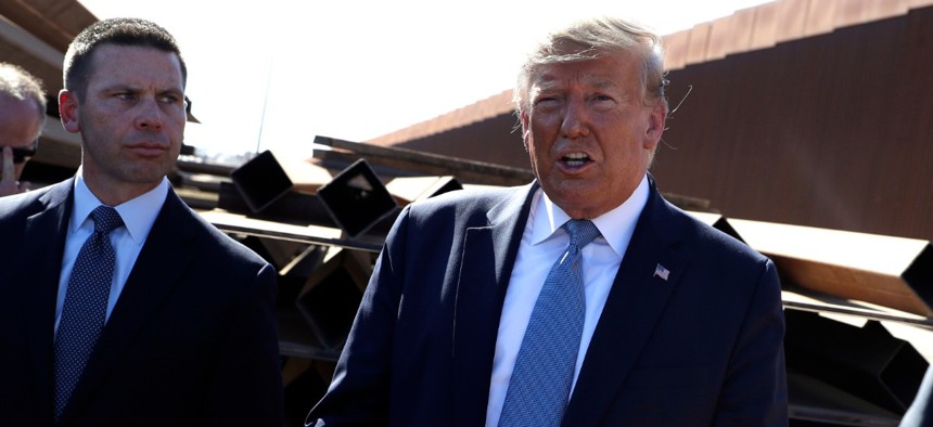 President Donald Trump talks with reporters as he tours a section of the southern border wall, in Otay Mesa, Calif., as acting Homeland Secretary Kevin McAleenan listens on Wednesday.