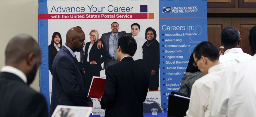 In this Aug. 4, 2011 photo, job seekers line up at the U.S. Postal Service booth during a career job fair in Arlington, Va. 