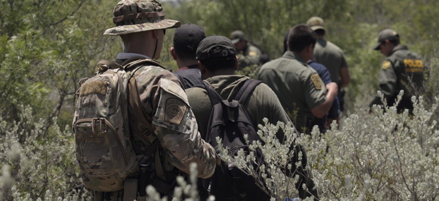 Four people apprehended by members of the U.S. Border Patrol Search, Trauma, and Rescue (BORSTAR) team are led to awaiting vehicles near Eagle Pass, Texas in June.
