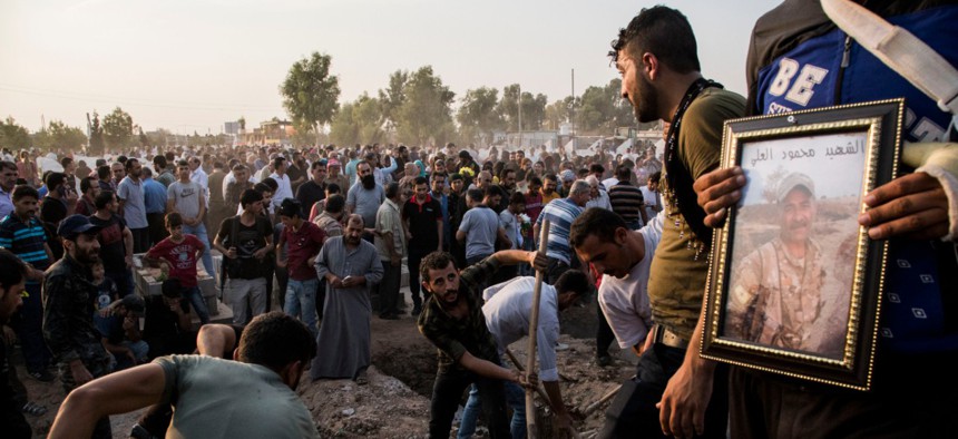 Syrians bury Syrian Democratic Forces fighters killed fighting Turkish advance in the Syrian town of Qamishli, Saturday, Oct. 12, 2019, Turkey's military says it has captured a key Syrian border town Ras al-Ayn under heavy bombardment.