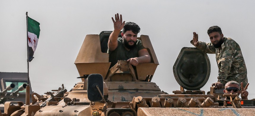 Turkish-backed Syrian opposition fighters on an armoured personnel carrier wave as they drive to cross the border into Syria, in Akcakale, Sanliurfa province, southeastern Turkey, on Friday.