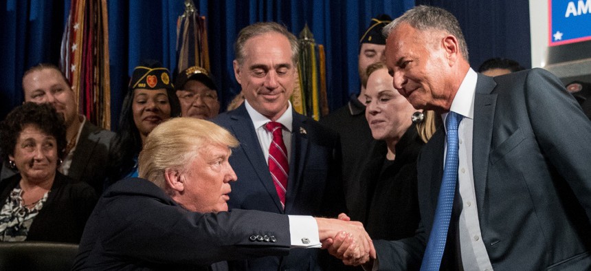 Donald Trump, left, accompanied by Veterans Affairs Secretary David Shulkin, center, shakes hands with Isaac "Ike" Perlmutter, an Israeli-American billionaire, and the CEO of Marvel, right, before signing an executive order in 2017.