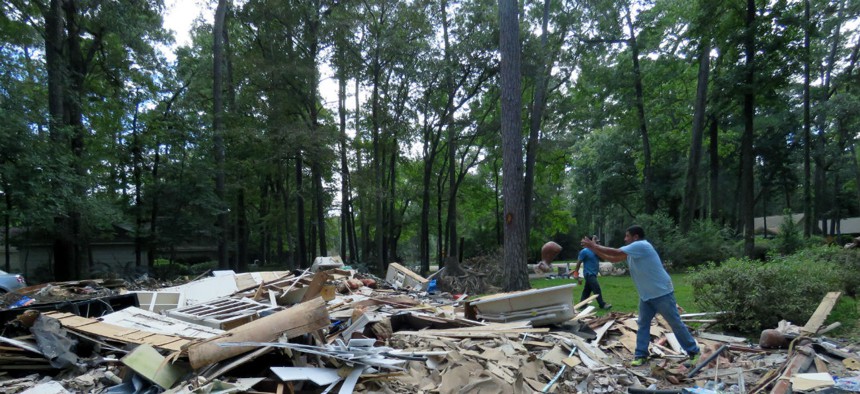 Workers clear debris from a home damaged by Hurricane Harvey. 