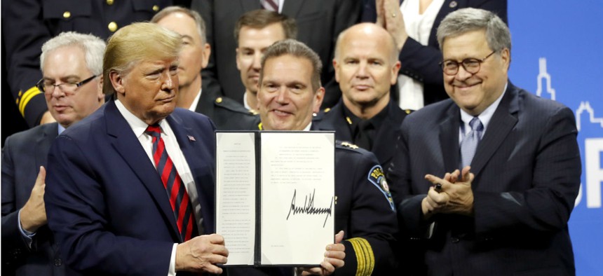 President Trump displays his signature after signing an executive order creating a commission to study law enforcement and justice at the International Association of Chiefs of Police Convention on Oct. 28.